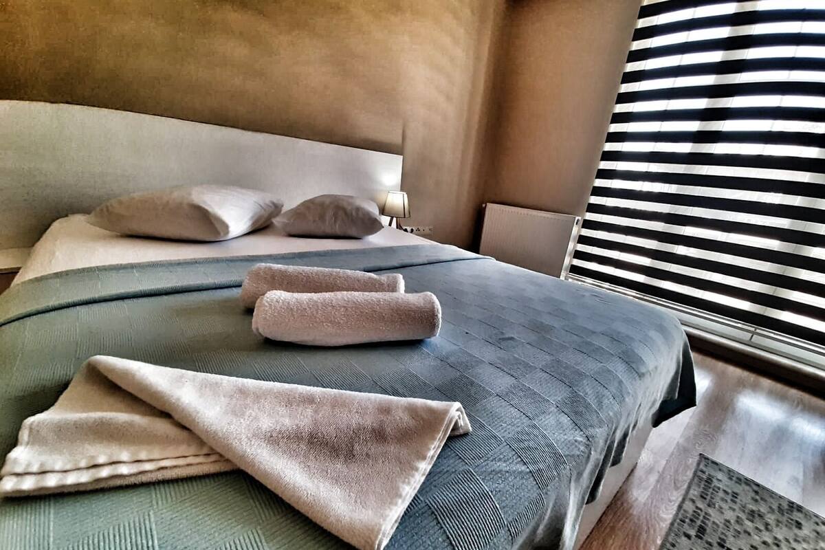 Una habitació d'hotel amb un llit, almoines i una finestra amb persianes.