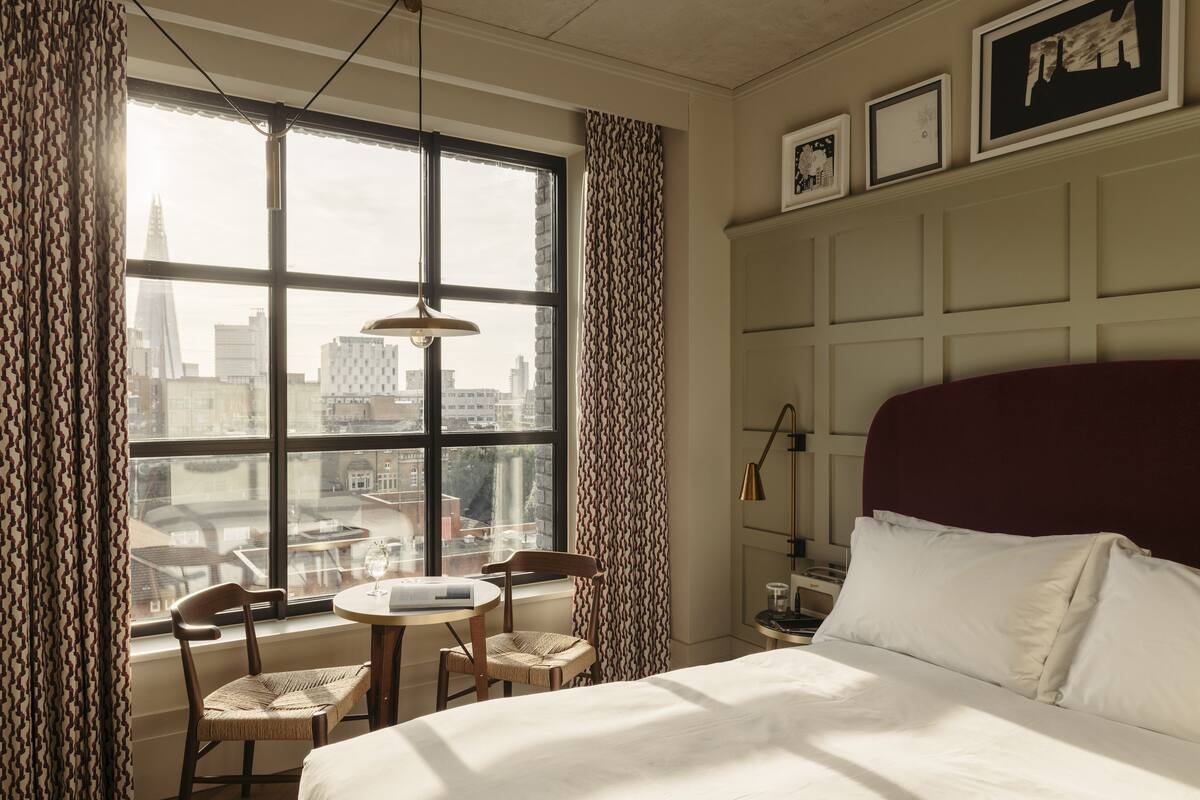 Ein Hotelzimmer mit großem Fenster, einem Bett, einem runden Tisch und zwei Stühlen.