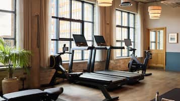 Ein Fitnessraum mit Laufbändern, Ergometer und einer Bank.