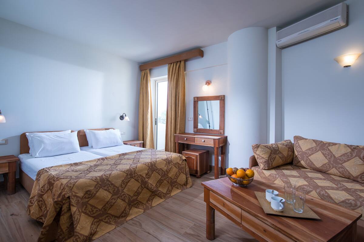 Habitació d'hotel amb dos llits, un escriptori de fusta, un bol de fruita i un mirall.