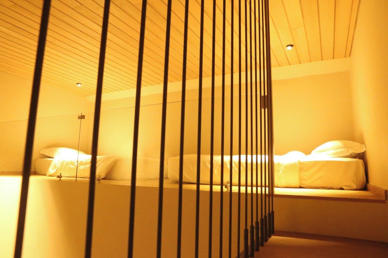 Habitación de hotel con dos camas, techo de listones de madera y una decoración con colores cálidos.