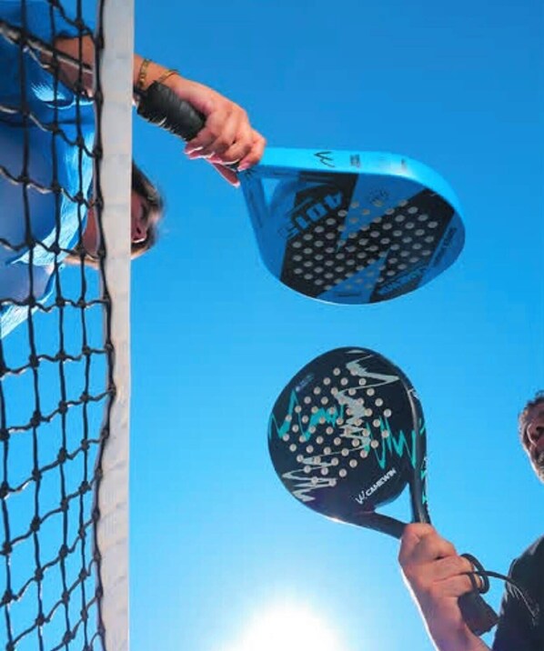 A person holding a tennis racket with a blue and black design, and another racket with a similar design.
