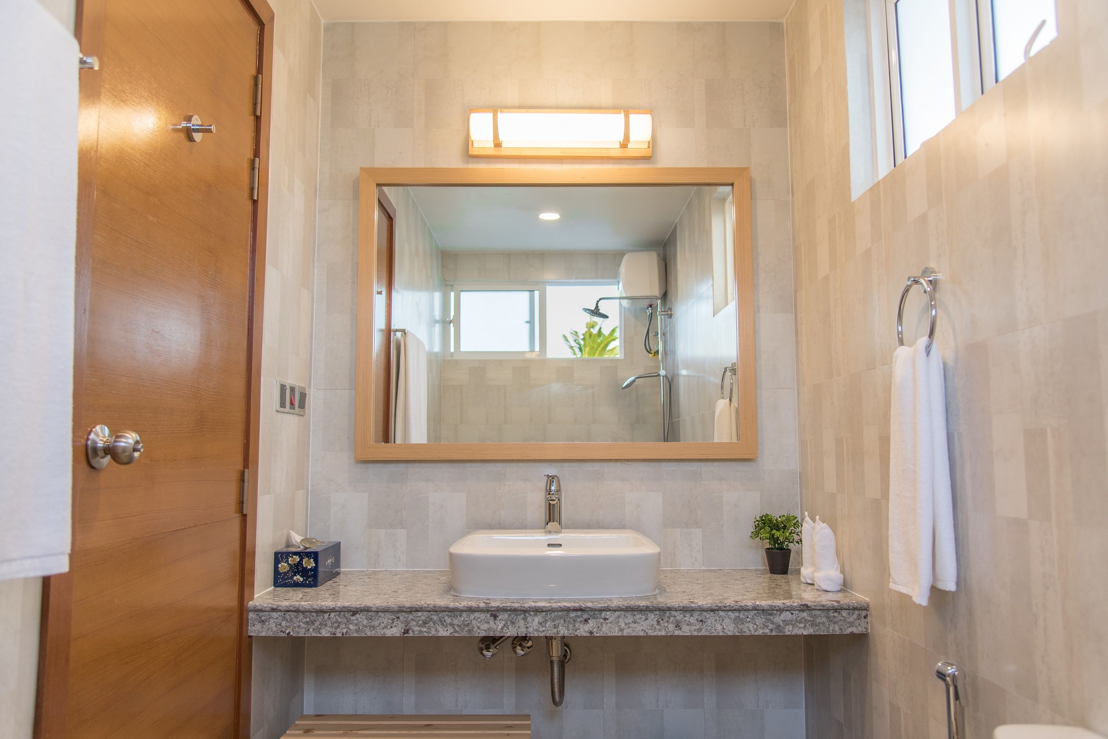 A bathroom with a wooden door, a sink with a mirror above it, and a towel rack.