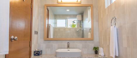 A bathroom with a wooden door, a sink with a mirror above it, and a towel rack.