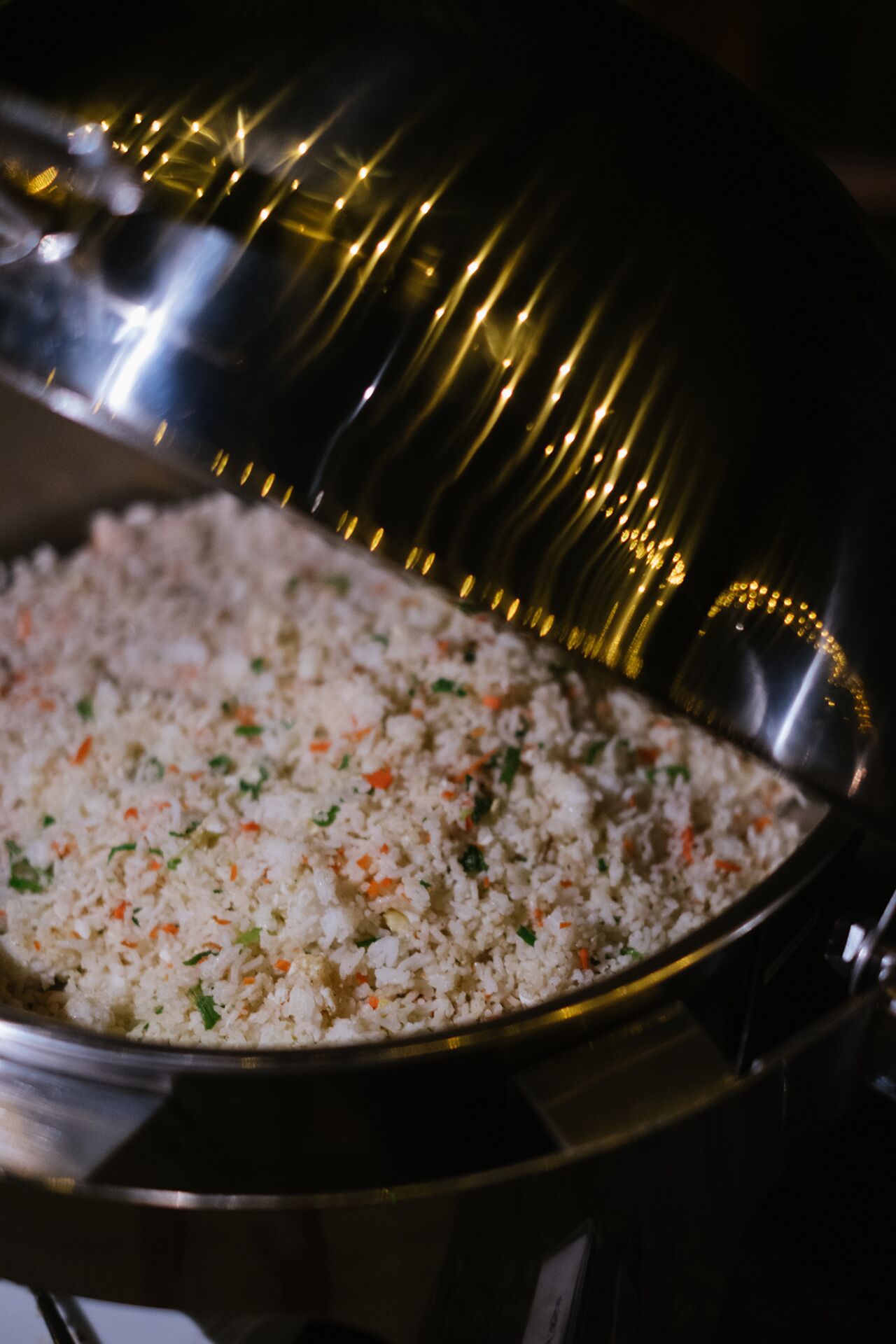 A large metal serving dish filled with rice mixed with vegetables.