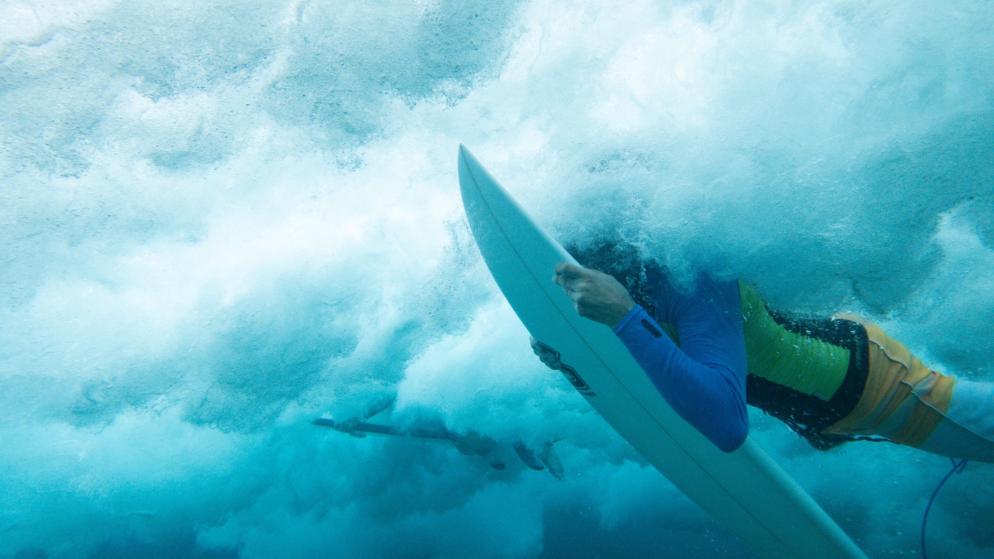 A person holding a surfboard underwater, suggesting an aquatic environment.