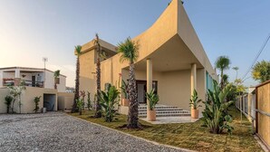 A modern building with a sloped roof, a covered entrance, and a gravel driveway. - Hostal Sahaba Zahora (Barbate)
