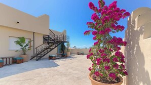 A rooftop patio with a staircase, outdoor seating, and a potted bougainvillea plant. - Hostal Sahaba Zahora (Barbate)
