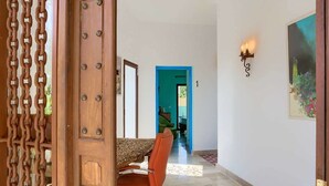 A dining area with a table and chairs, a blue door, and a wall-mounted light fixture. - Hostal Sahaba Zahora (Barbate)