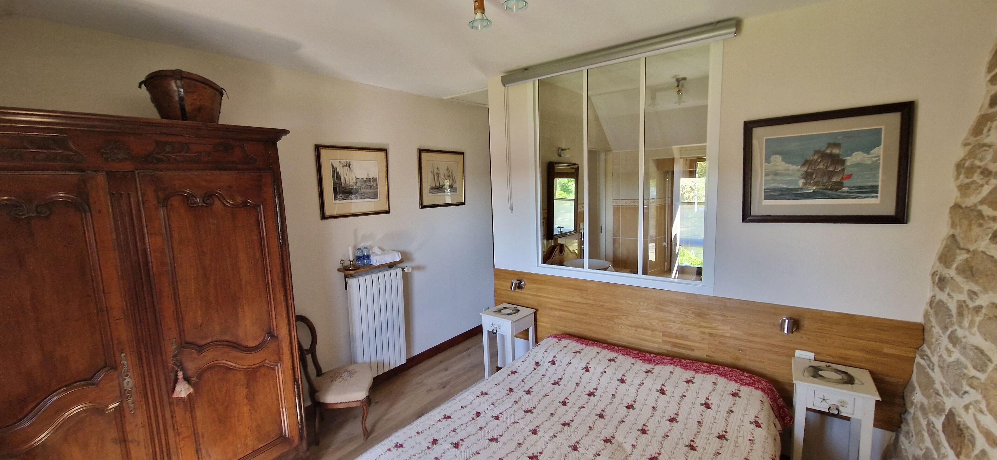Un dormitorio con una cama grande, un armario de madera, un radiador y una ventana con vistas al exterior.
