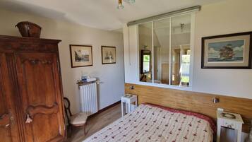 Un dormitorio con una cama grande, un armario de madera, un radiador y una ventana con vistas al exterior.