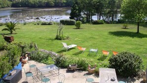 Un jardin au bord de la rivière, doté d’un espace extérieur aménagé et offrant une vue sur le fleuve.