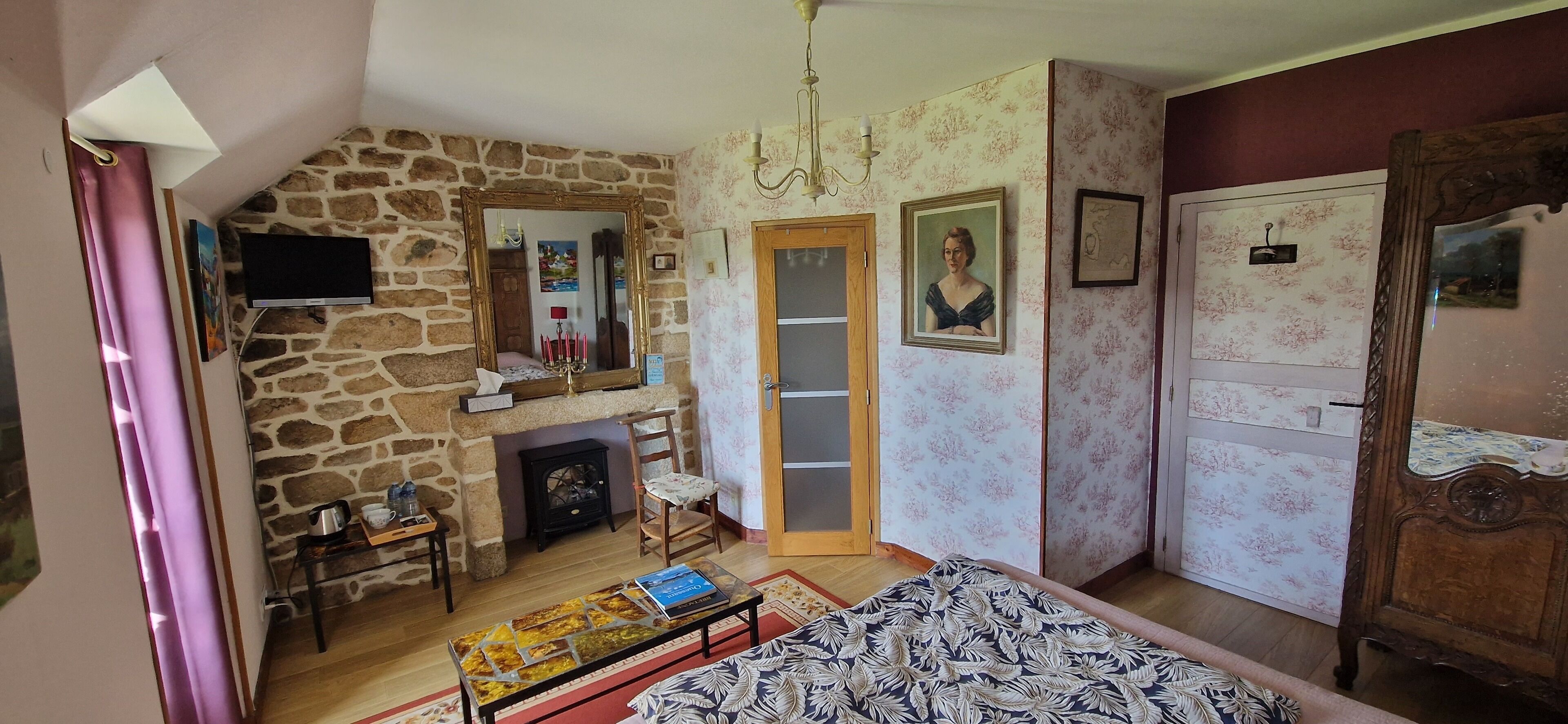 Una habitación acogedora con pared de piedra, chimenea, cama, cómoda de madera y espejo.