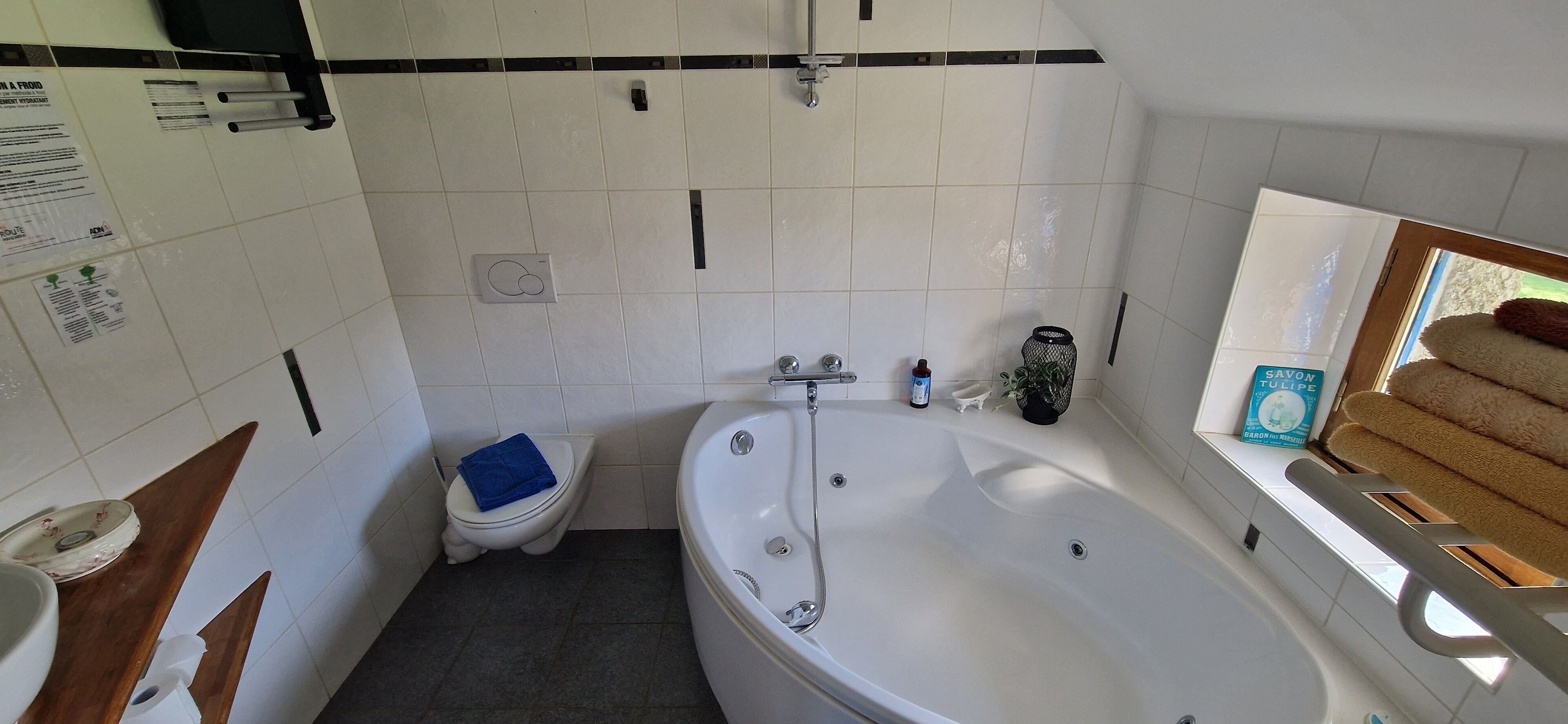 Une salle de bain avec une baignoire, des toilettes et une fenêtre, ainsi que des serviettes.