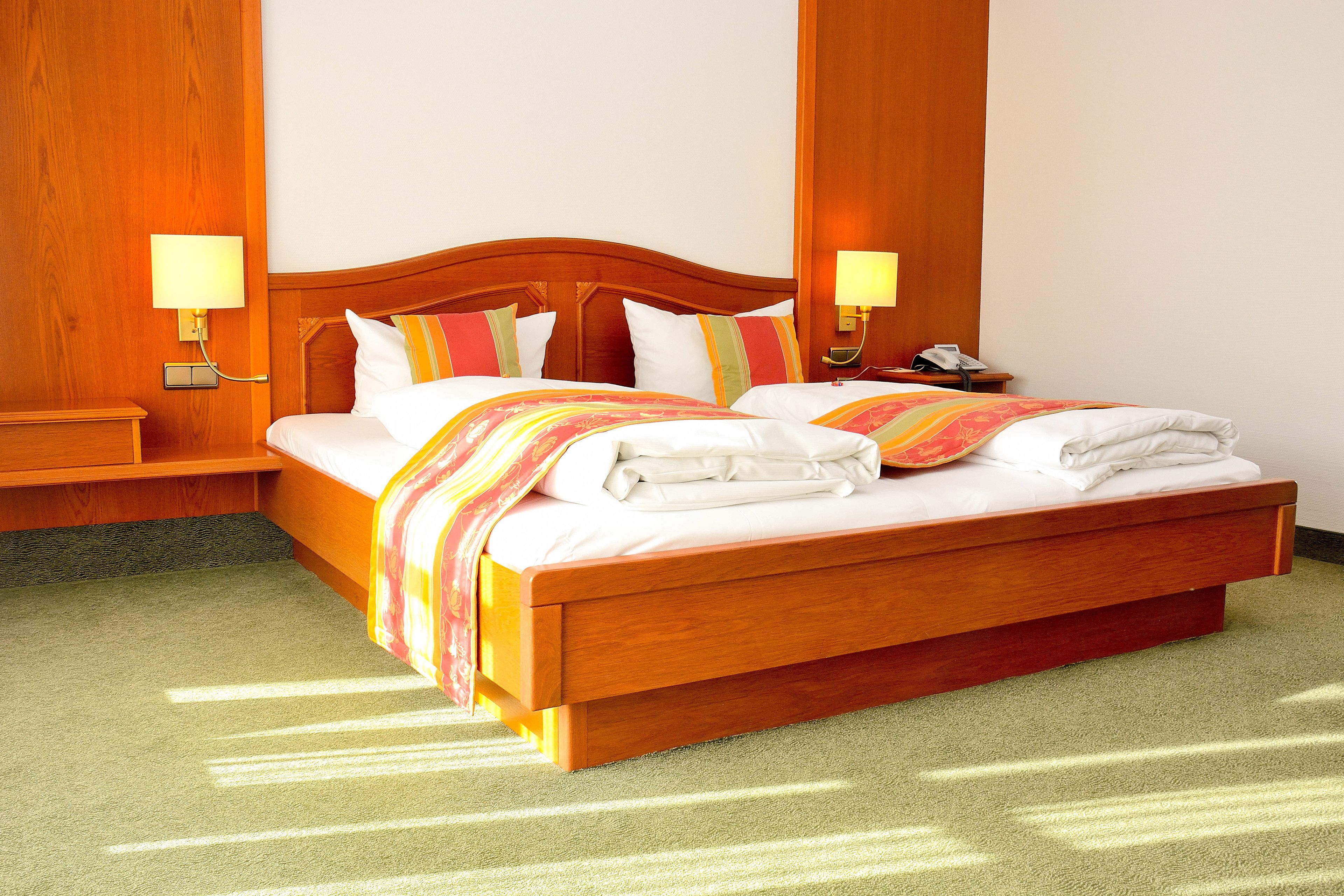 A hotel room with a wooden bed, two bedside tables, and two wall-mounted lamps.