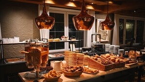 A buffet setup with various food items and serving utensils, including baskets and containers, in a well-lit room with large windows. - Hotel Brauerei Gasthof Höhn (Memmelsdorf)