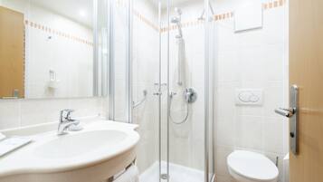 Un baño moderno con ducha de vidrio, lavamanos con espejo e inodoro.