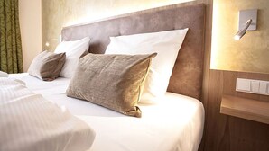 A hotel room with a large bed, multiple pillows, a headboard, and a wall-mounted light fixture. - Hotel Brauerei Gasthof Höhn (Memmelsdorf)