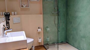 Un bany modern amb dutxa tancada per vidre, un tocador de fusta i una paret beix.