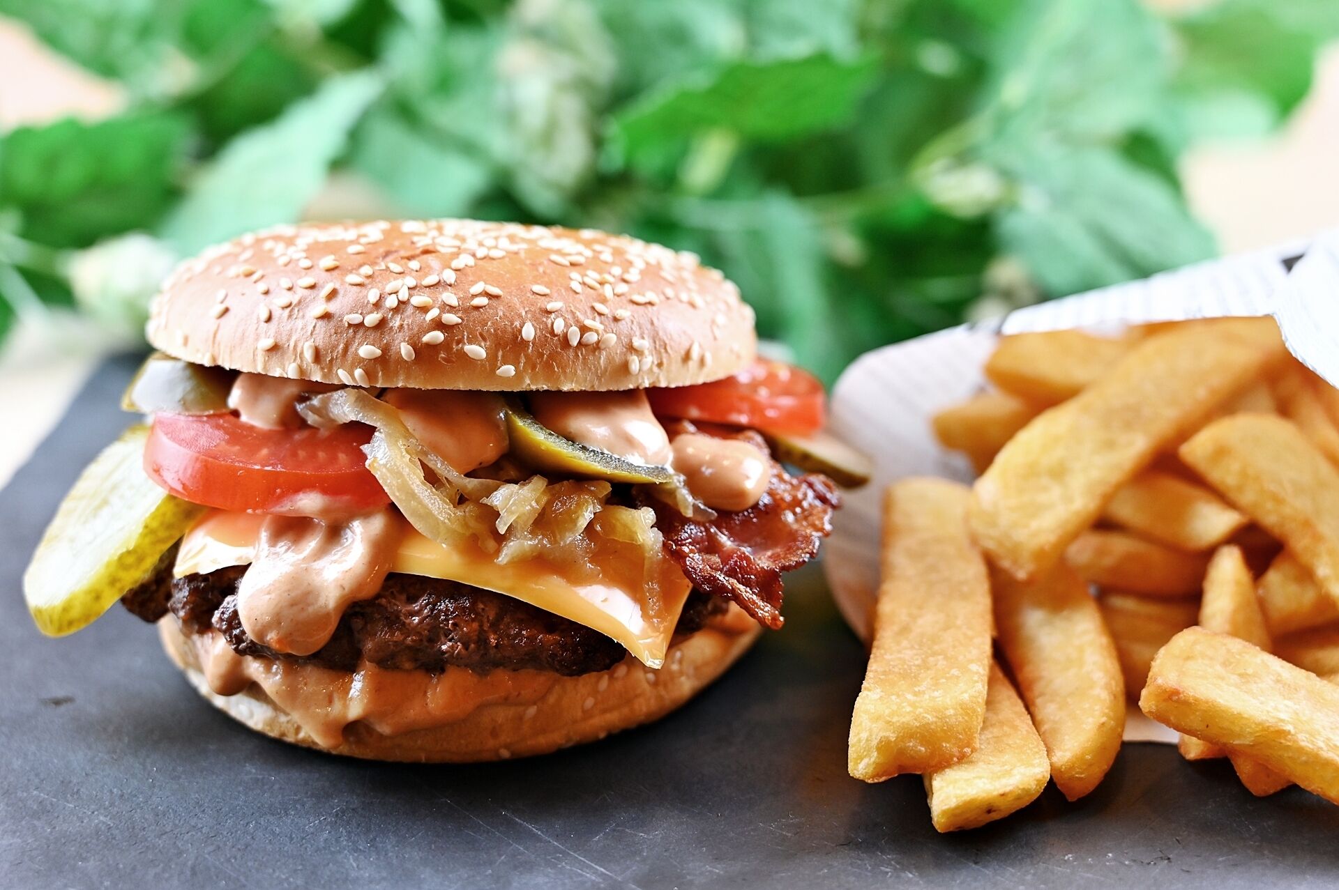 A burger with lettuce, tomato, and pickles, and a side of fries.