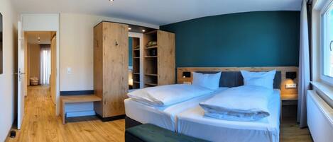 Un dormitorio con una cama grande, un armario de madera, un banco y un vestidor.