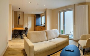 Una sala de estar moderna con un sofá, una mesa de comedor y una cocina al fondo.