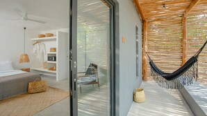 A modern room with a glass door leading to a hammock and a seating area. - Tamu Koh Rong (Koh Rong)