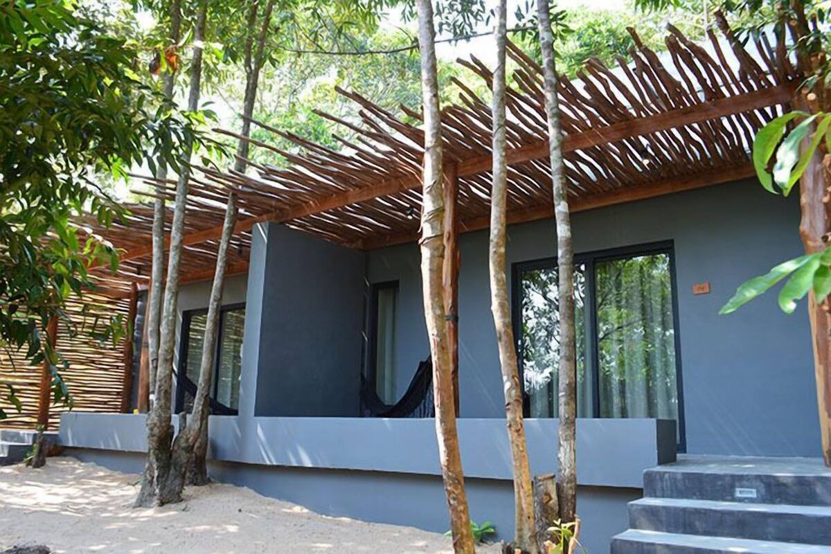 A modern building with a grey facade, large windows, and a wooden pergola structure.