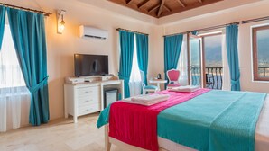 Ein Schlafzimmer mit Bett, Schreibtisch, Fernseher und einem Balkon mit Blick.