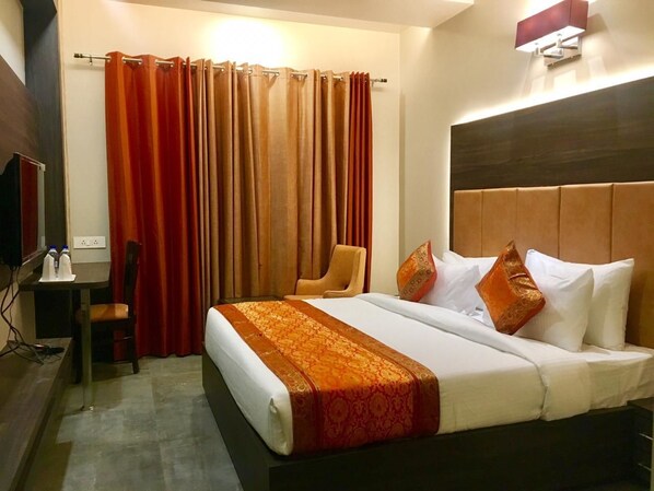 Una habitación de hotel con una cama, una silla, un escritorio con un ordenador y un televisor.