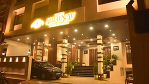 Hotel Ashinav International -hotellin moderni sisäänkäynti, edessä parkkeerattu auto ja sisäänkäyntiin johtavat portaat.