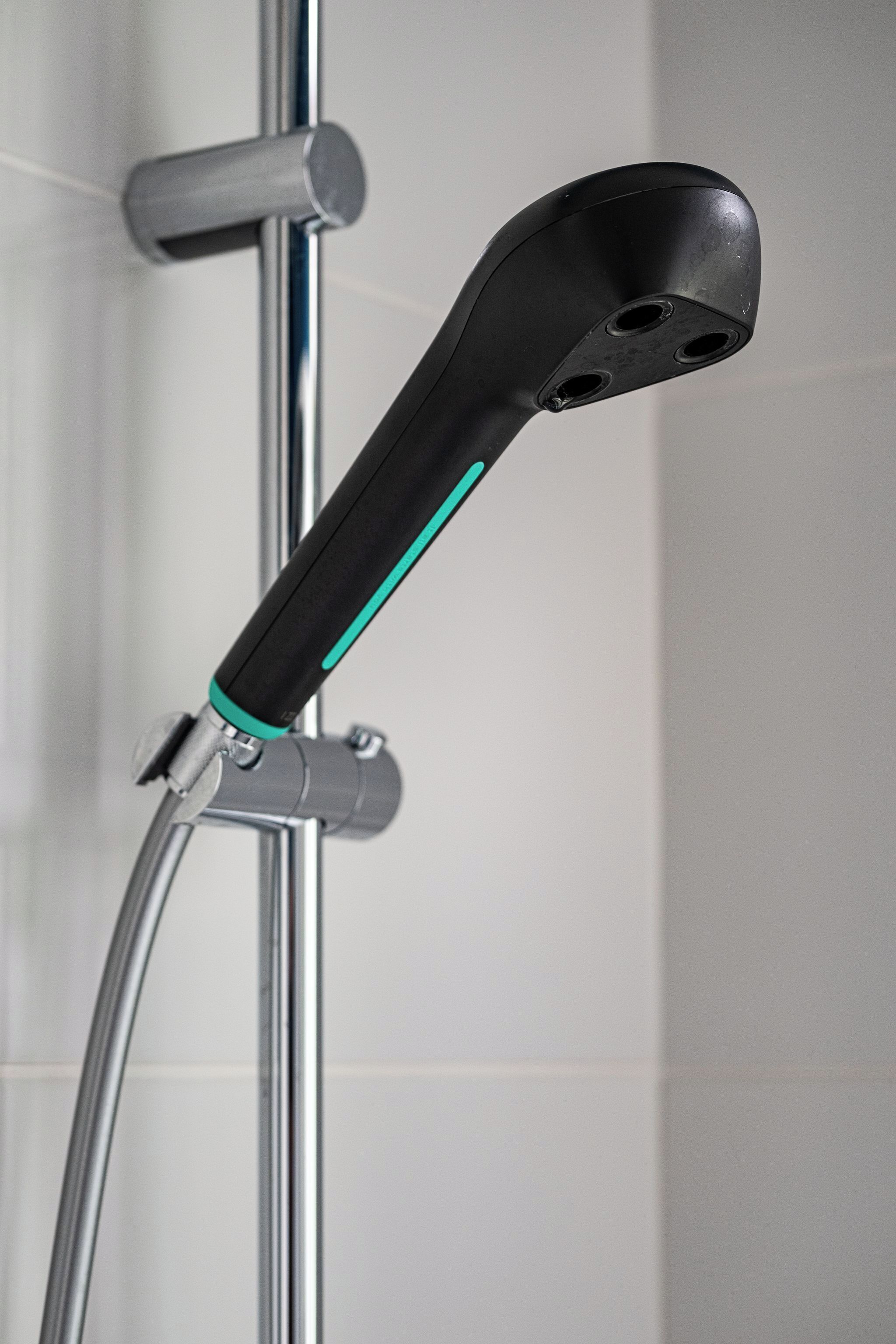 A showerhead with a black handle and a chrome shower hose.