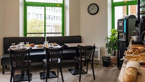 Um café acolhedor com piso de madeira, um sofá preto e uma máquina de café.