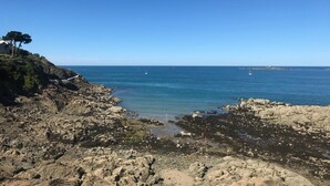Litoral rochoso com céu azul límpido e mar calmo.