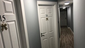 A hallway with white doors numbered 15 and 16, wooden flooring, and a light blue wall. - Brownlows Inn (Liverpool)