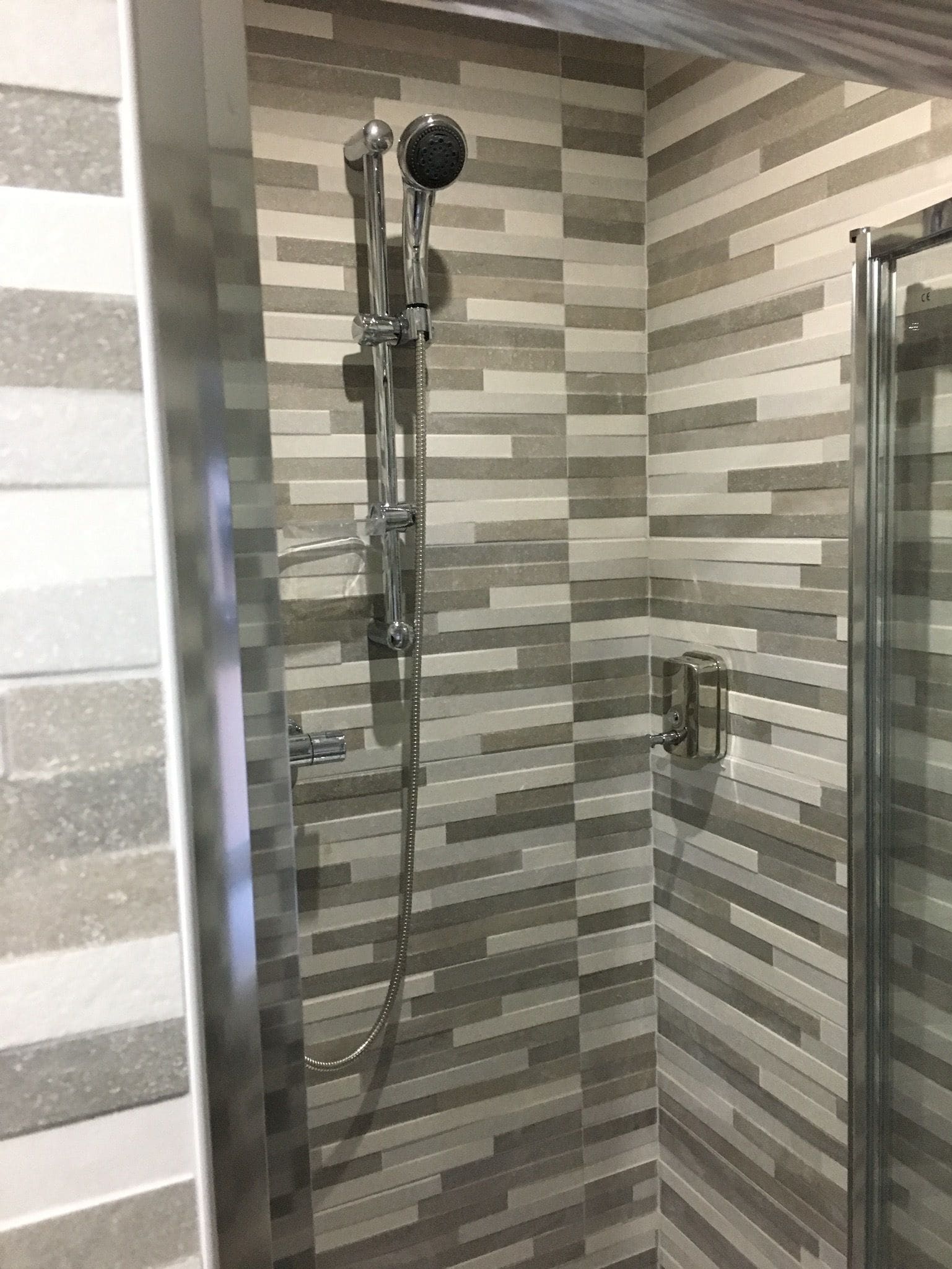 A shower with a handheld showerhead and a wall-mounted faucet.