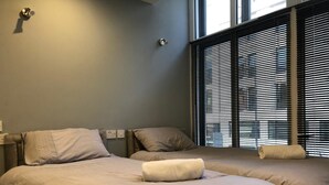 A room with two beds, a window with blinds, and a wall socket. - Brownlows Inn (Liverpool)