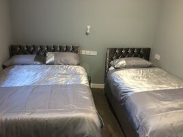 Two twin beds with tufted headboards in a room with light-colored walls.