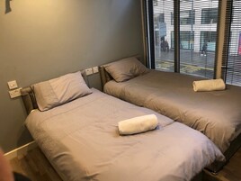 A twin bedroom with two beds, each with a pillow and a rolled towel.