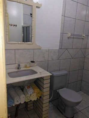 Un baño con lavamanos, espejo, inodoro y toallero.