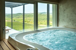 Un jacuzzi con vistas a un paisaje verde a través de amplios ventanales.