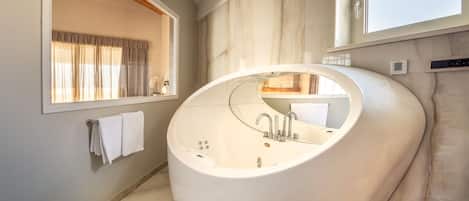 A modern bathroom with a large freestanding bathtub, a vanity with a mirror, and a window providing natural light.