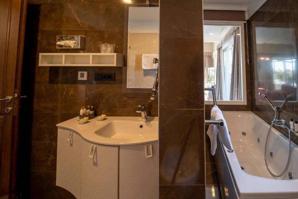 Een moderne badkamer met een marmeren wastafel, een badkuip en een wastafelmeubel met opbergruimte.