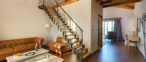 A spacious living area with a wooden staircase, leather furniture, and a dining table.