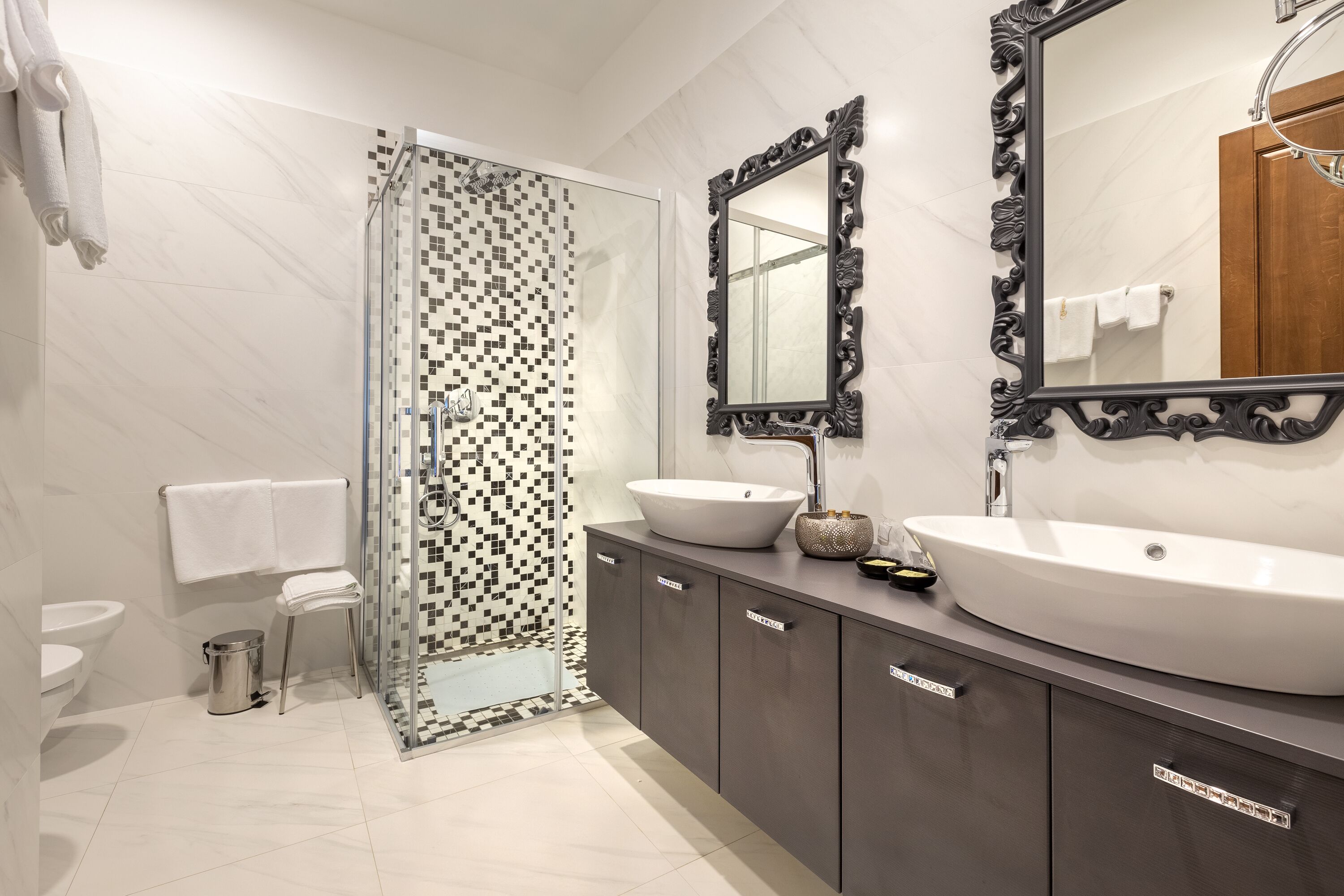 Un baño moderno con cabina de ducha de vidrio, dos lavamanos, un espejo grande y un inodoro.