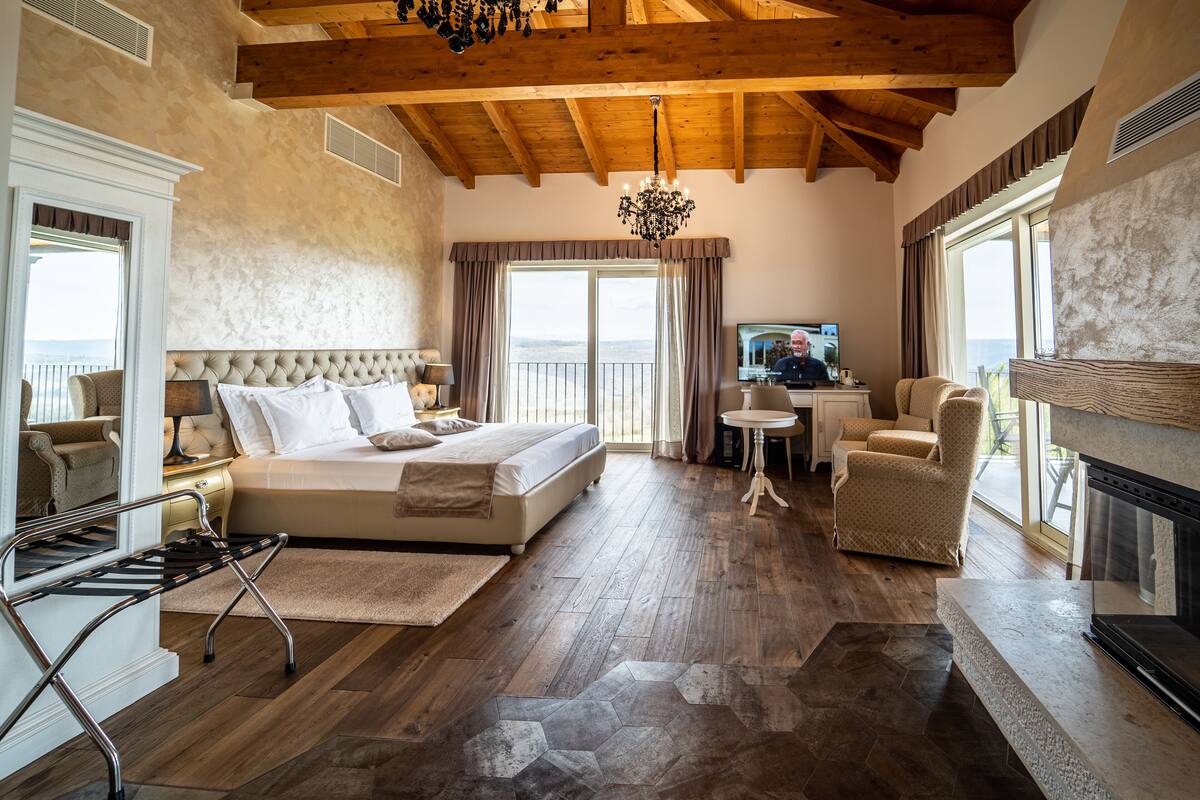 Een ruime slaapkamer met een groot bed, een televisie en een open haard.