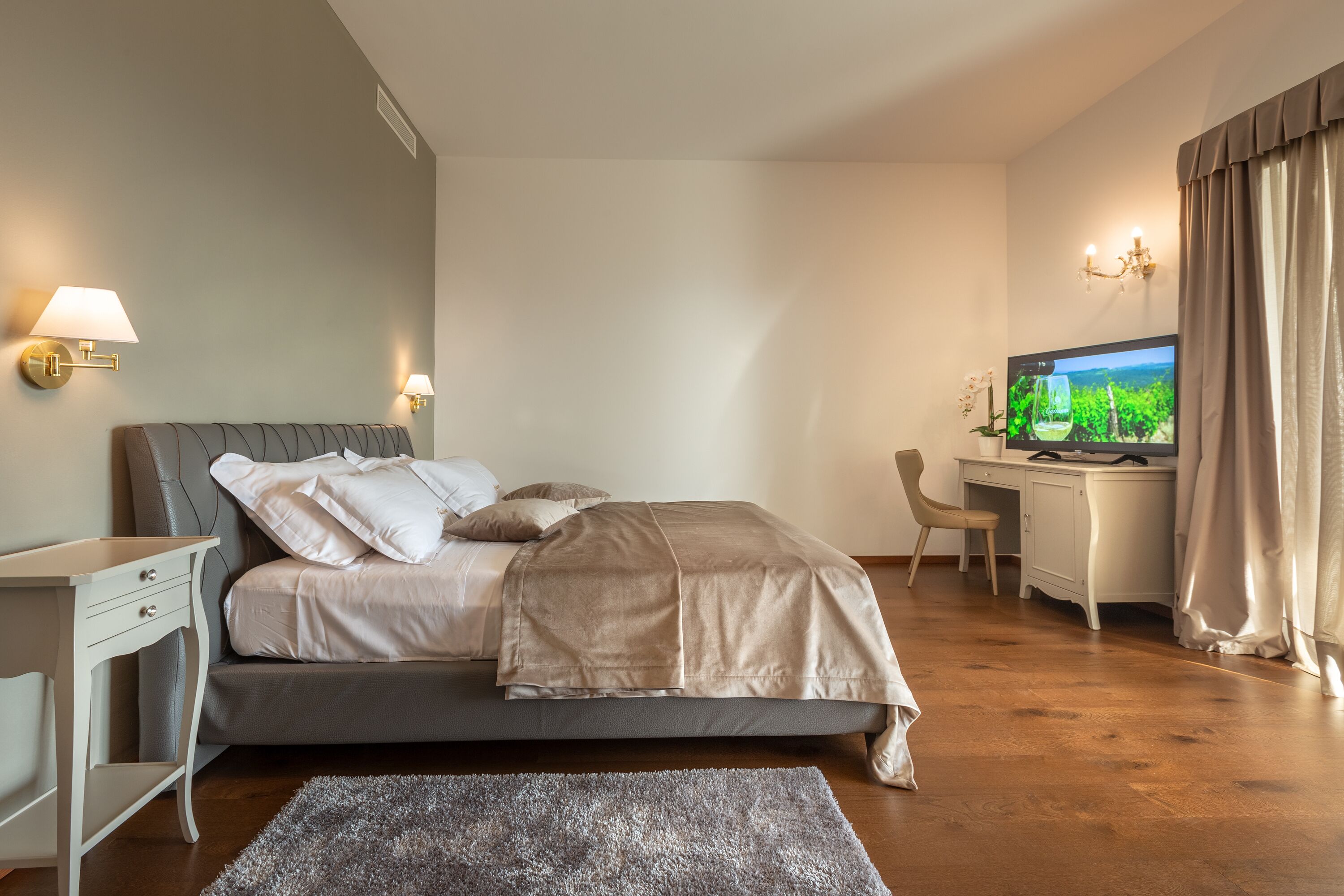 Un dormitorio moderno con cama, mesitas de noche, escritorio y televisor.