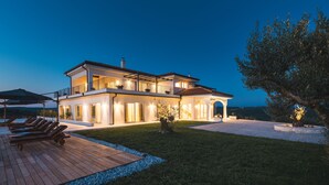 Een tweelaags huis met een patio, terrasmeubilair en een goed verlichte entree.