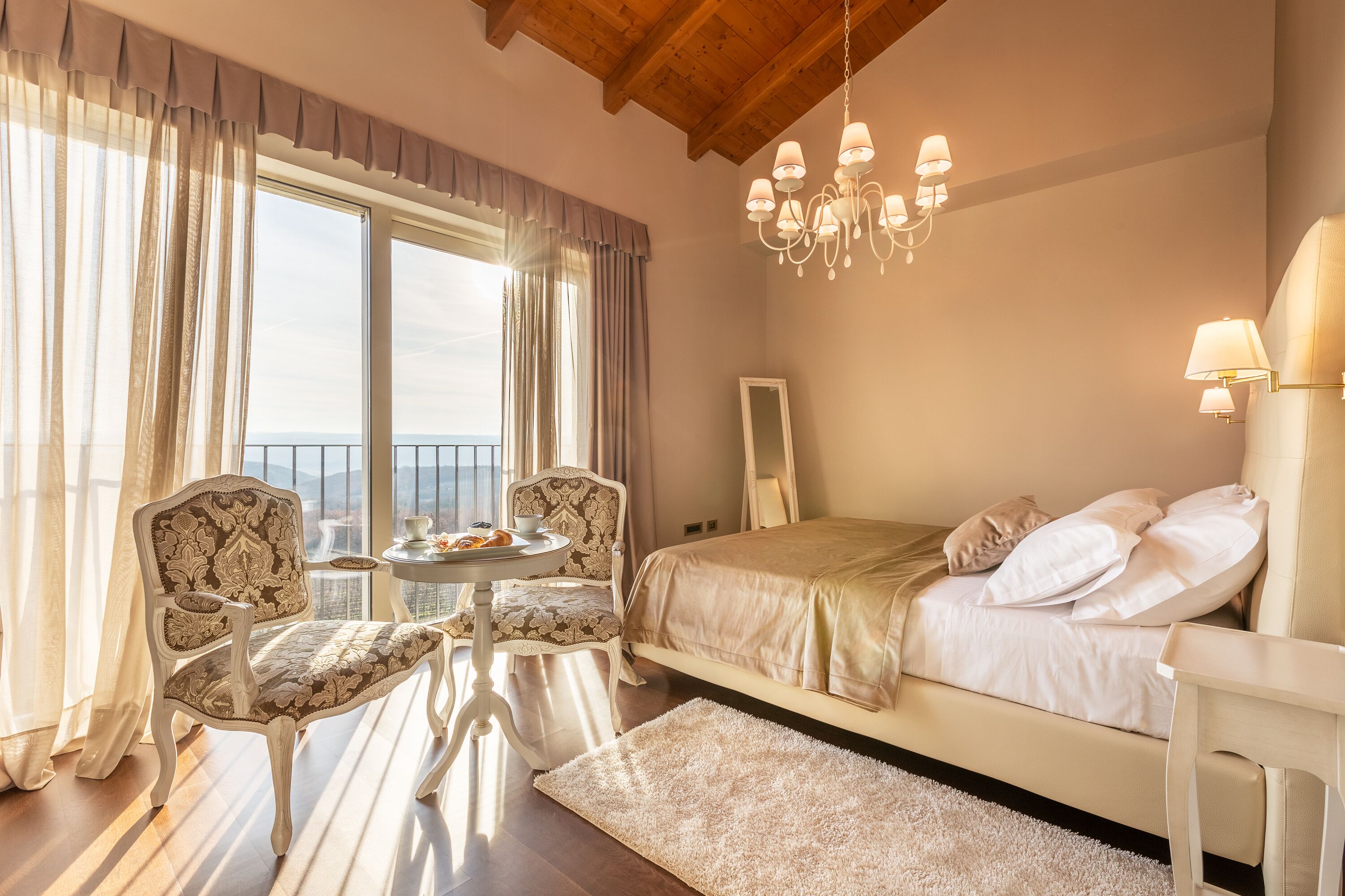 Ein Schlafzimmer mit einem Bett, zwei Stühlen, einem kleinen Tisch und einer Pendelleuchte.