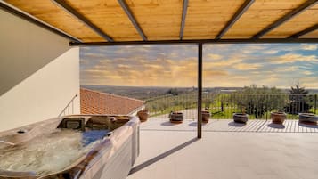 Une terrasse sur le toit avec un jacuzzi, des plantes en pot et une vue sur le paysage.